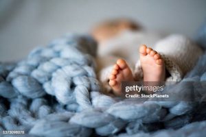 Foot of newborn baby on warm blanket